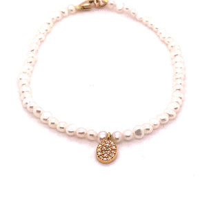 String of small pearls with golden clasp and gold oval diamond-covered charm