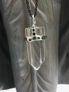 Clear quartz crystal attached to necklace by handmade silver "crown" that also features inset emeralds
