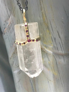 Clear quartz crystal attached to necklace by handmade gold "crown" that also features inset rubies