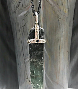 Green kyanite crystal attached to necklace by handmade silver "crown" that also features inset diamonds and sapphire
