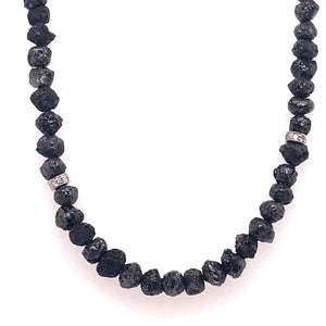 Rough cut black diamond spheres shapes form a necklace. White diamond rings intercept necklace at few points