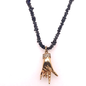 Rough cut black diamonds form a sort of beaded necklace. Gold hand with diamonds at base making the love sign is attached to necklace