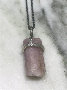 Light pink tourmaline crystal attached to necklace by handmade silver "crown" that also features inset diamonds