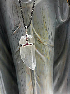 Clear quartz crystal attached to necklace by handmade silver "crown" that also features inset rubies