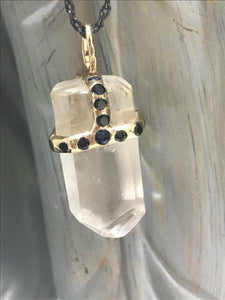 Clear quartz crystal attached to necklace by handmade gold "crown" that also features inset sapphires